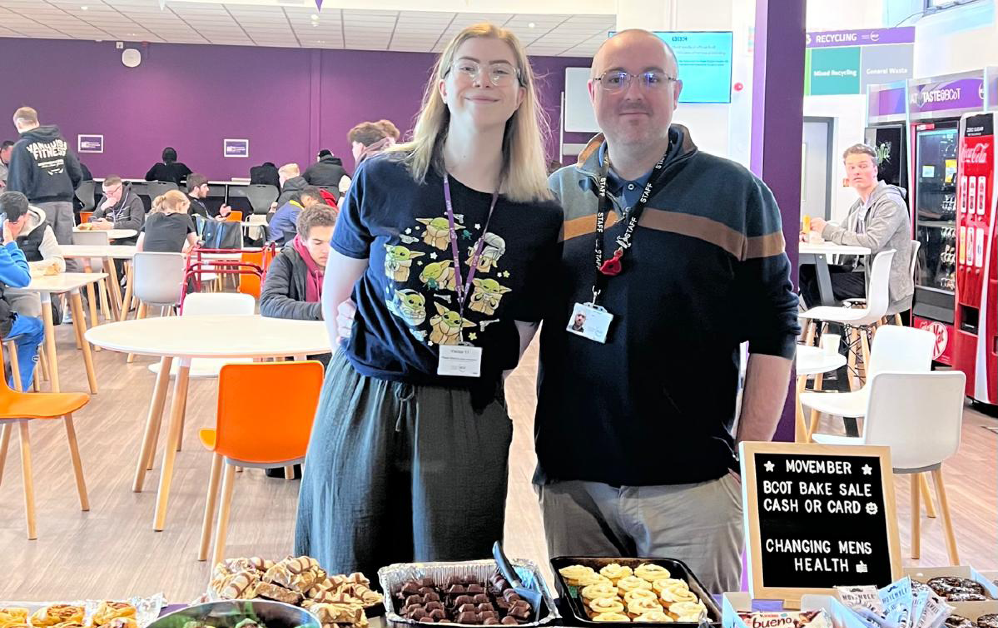 Male and Female stood behind cake stall