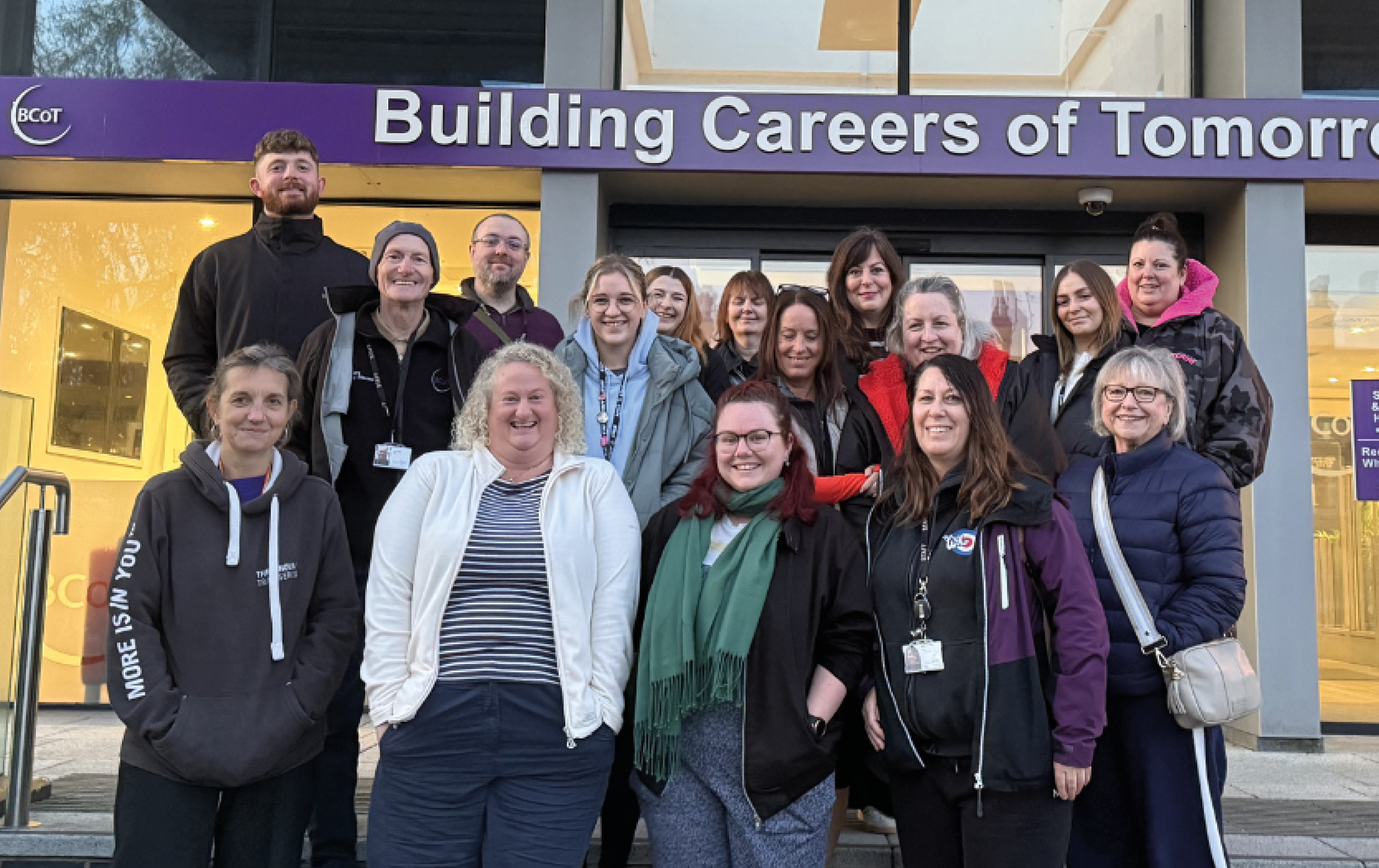 Staff smiling outside front of college ready for Dawn Walk